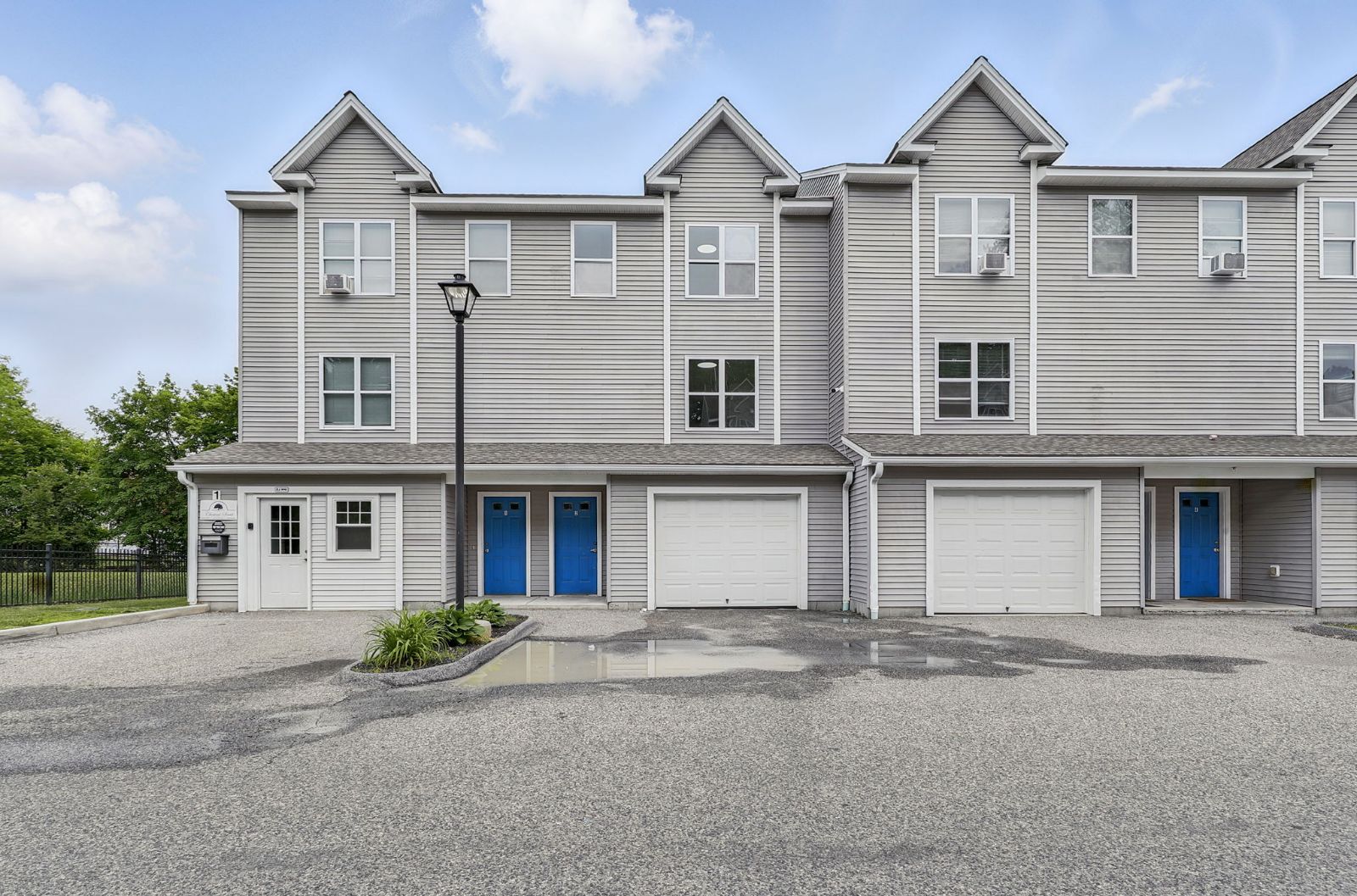 Front of the Chestnut Street townhomes: gray clapboard buildings with blue front doors and garages