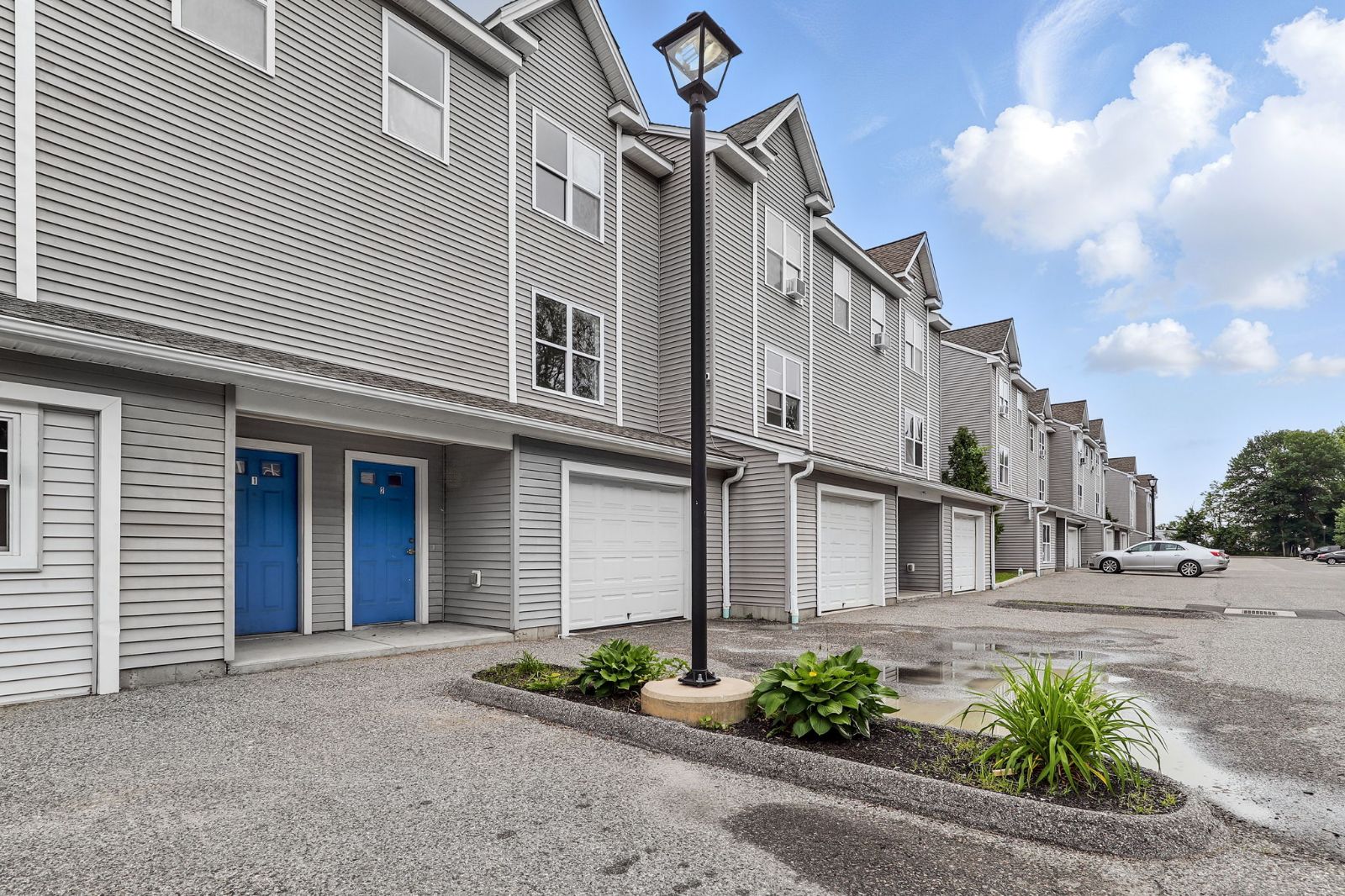 Row of townhomes with garages, a lamp post and a planted island