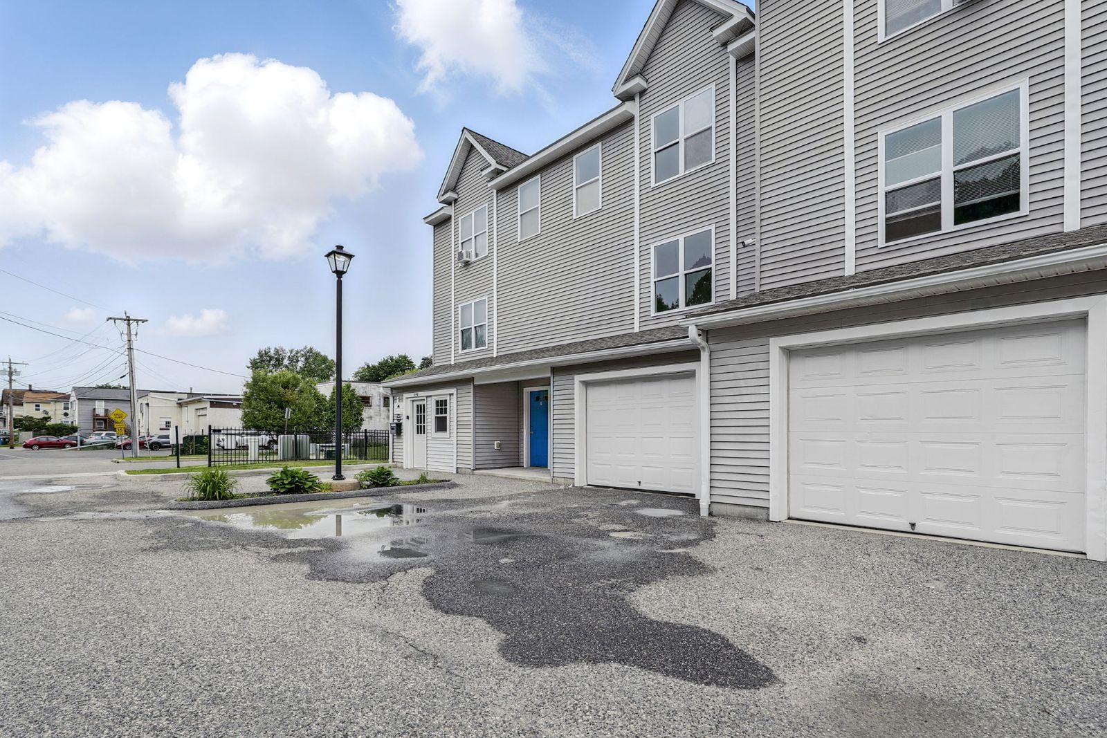 Townhomes and drive under a partly cloudy sky