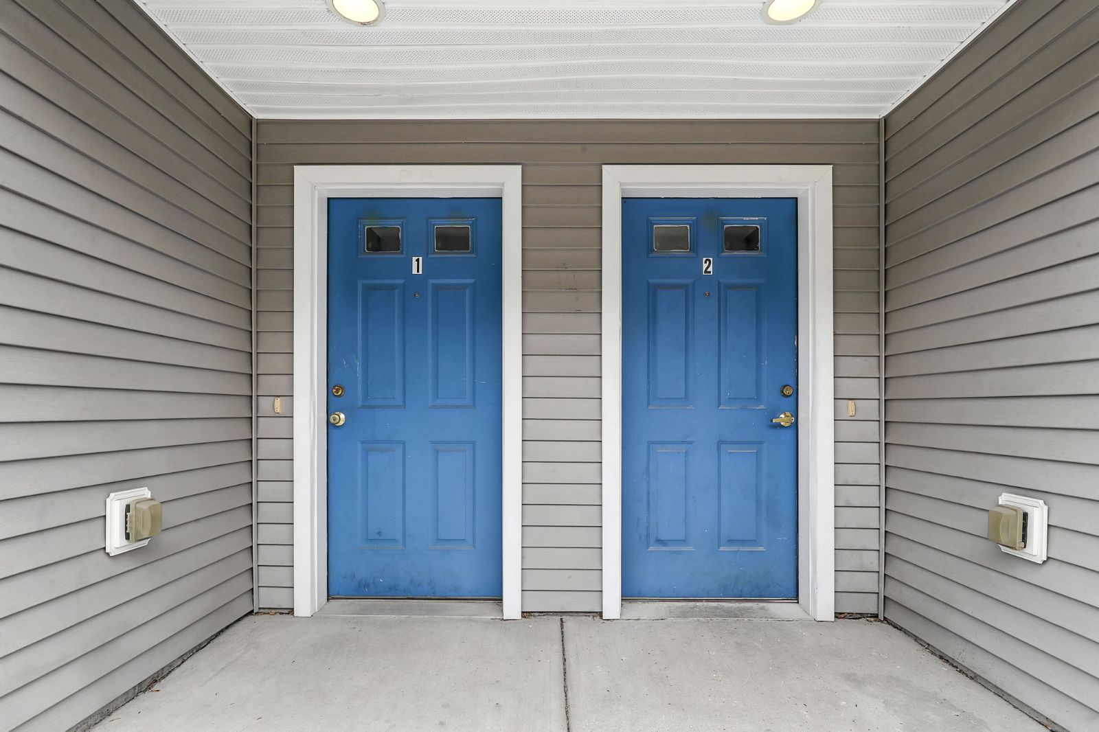 Two blue front doors side by side beneath a covered entry