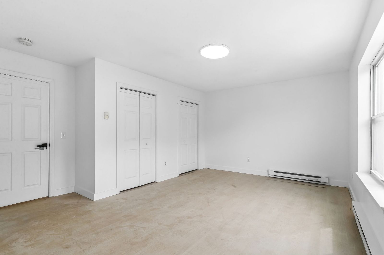 Bedroom with double closets and light wood-look flooring