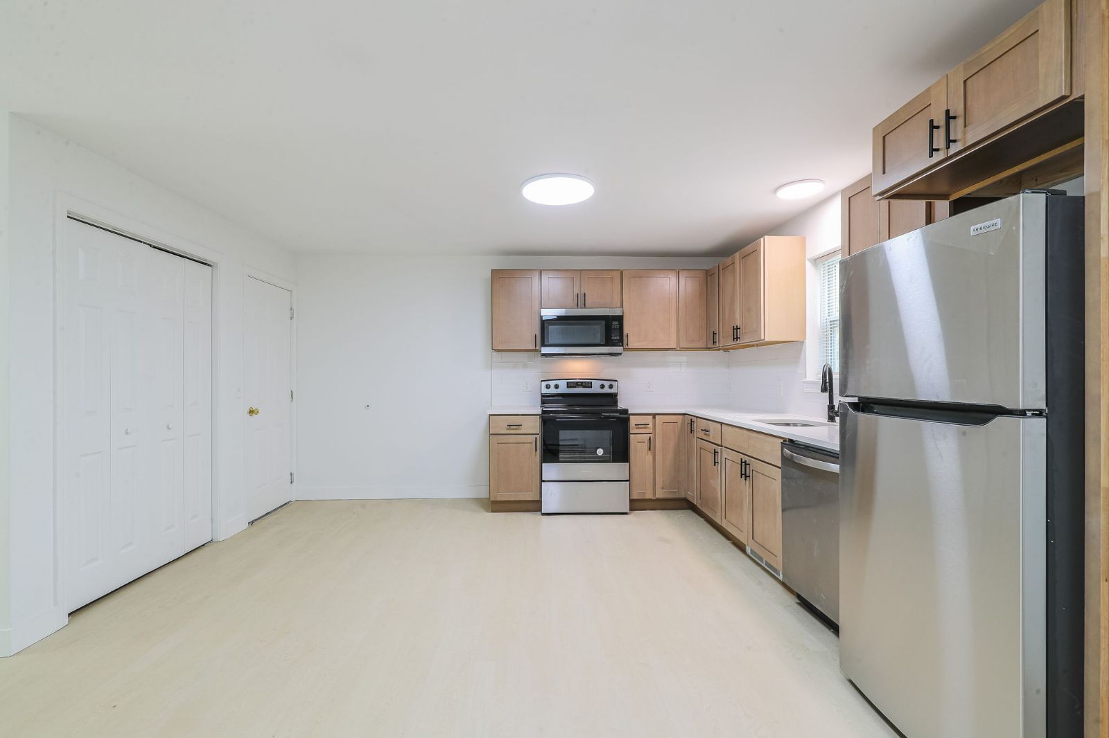 Open kitchen with stainless refrigerator beside a wall of closets