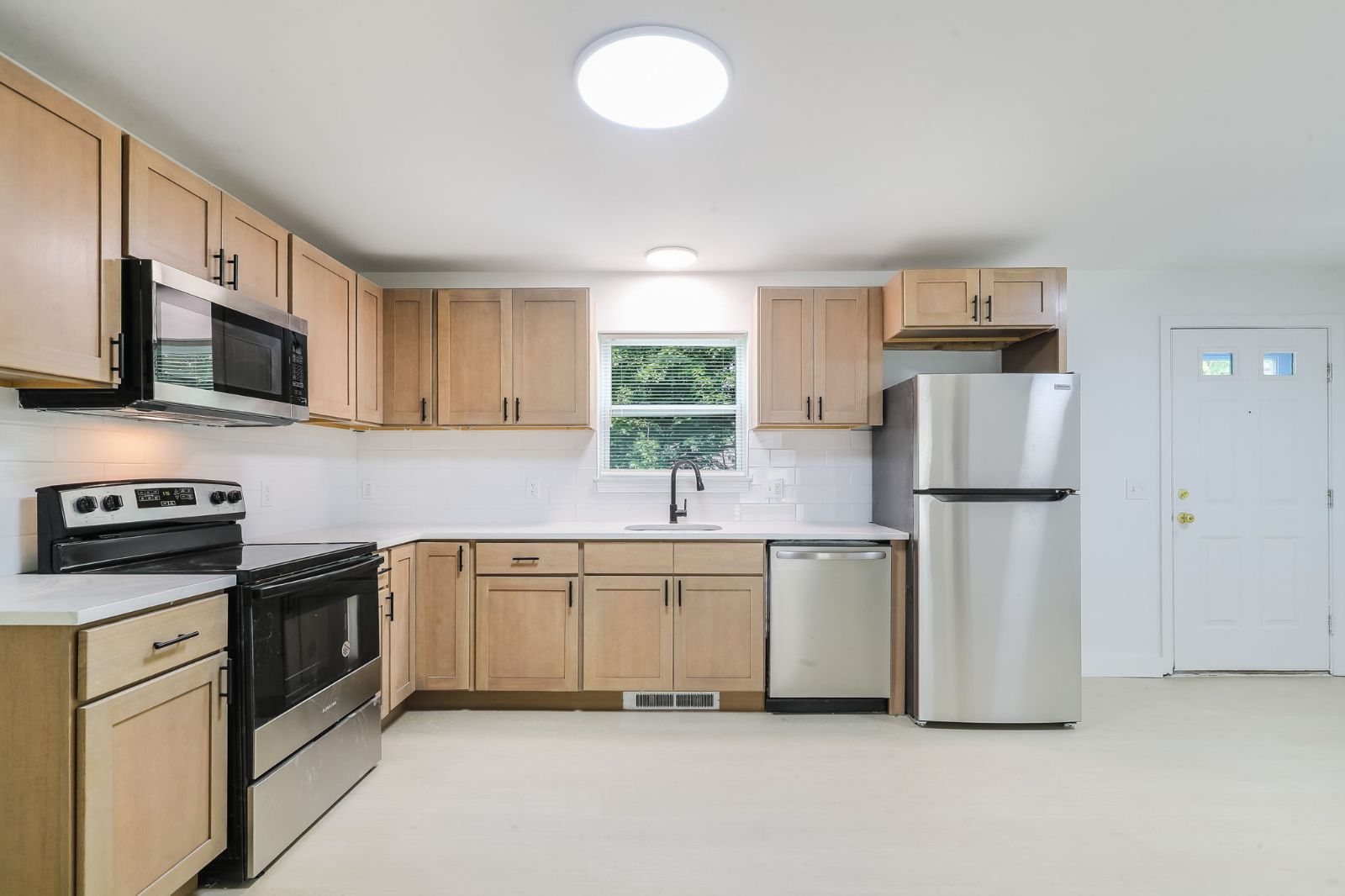 Kitchen with light wood cabinets, white counters and stainless-steel appliances