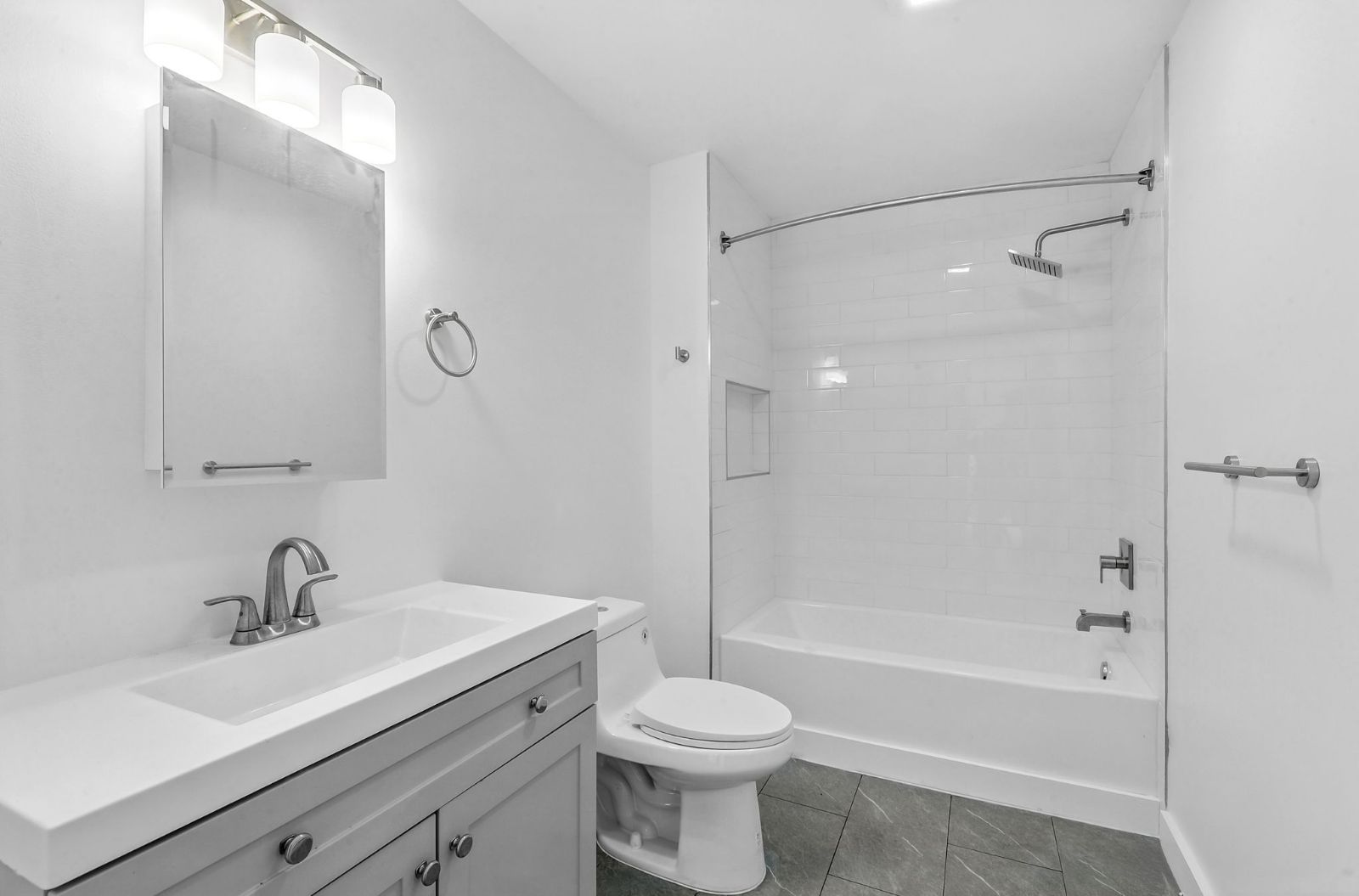 Bathroom with gray vanity, lit mirror, and tub with shower
