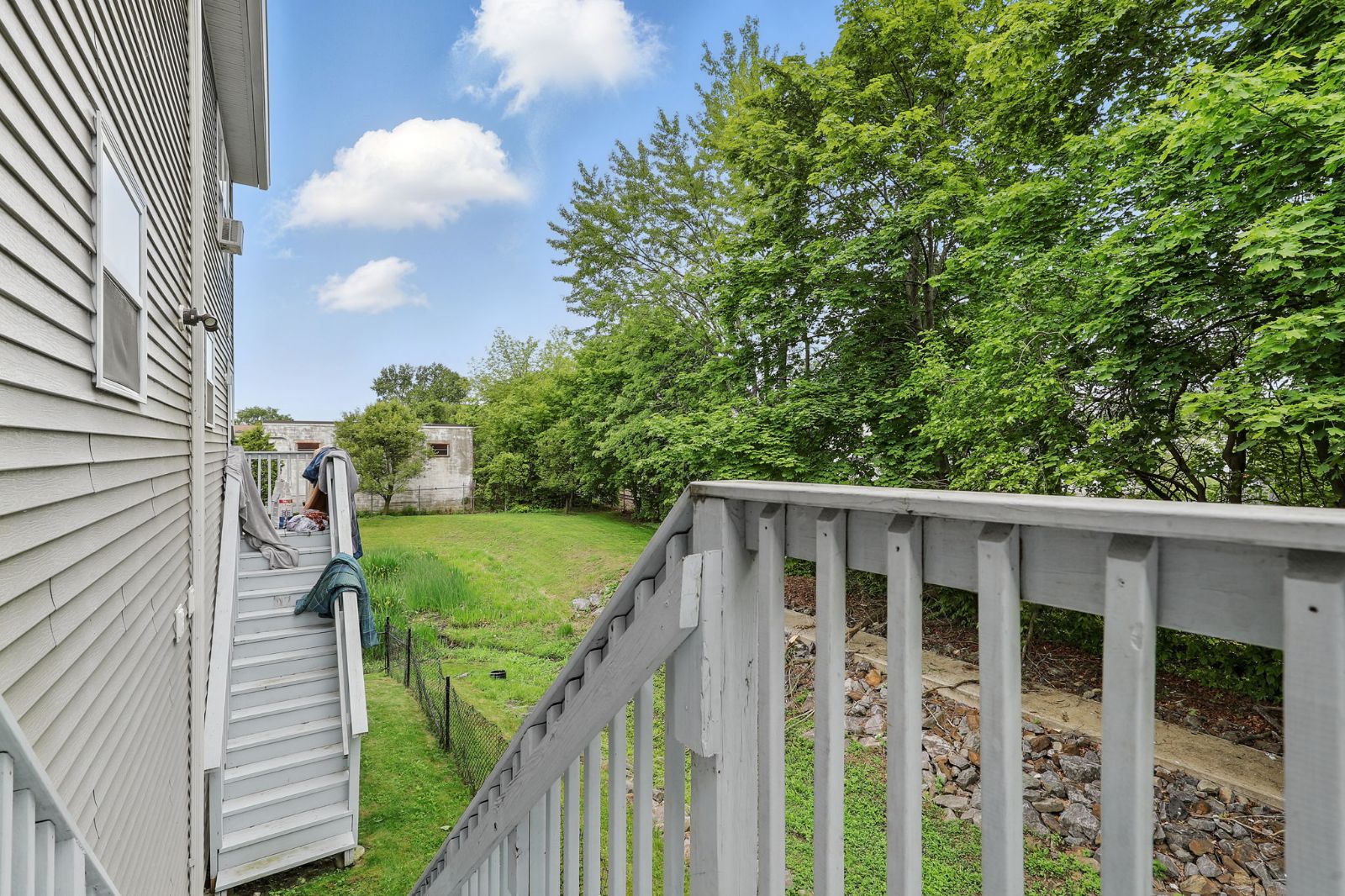 Back stairs and deck beside a green lawn and trees