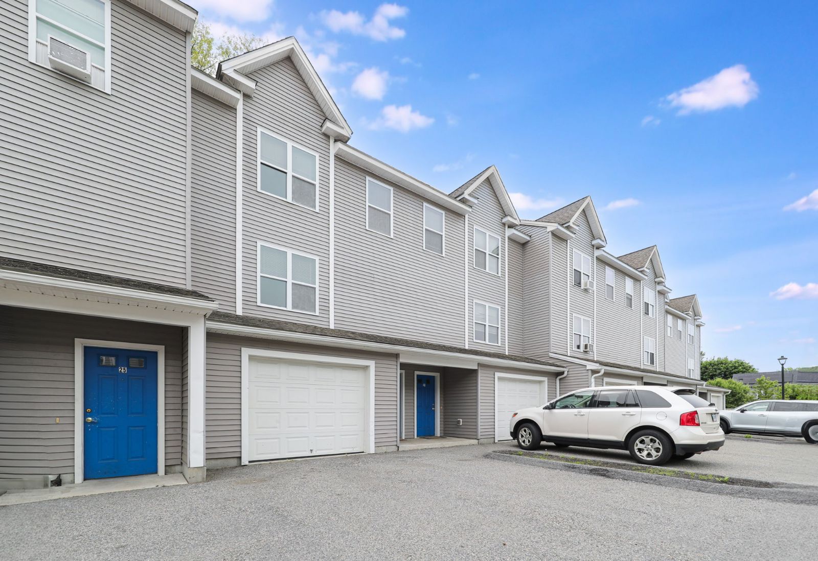 Townhome row with blue doors and garages under a blue sky