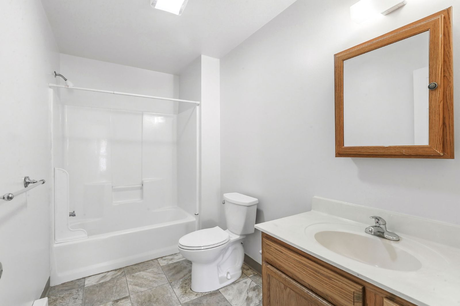 Bathroom with tub and shower, vanity, and wood-framed mirror