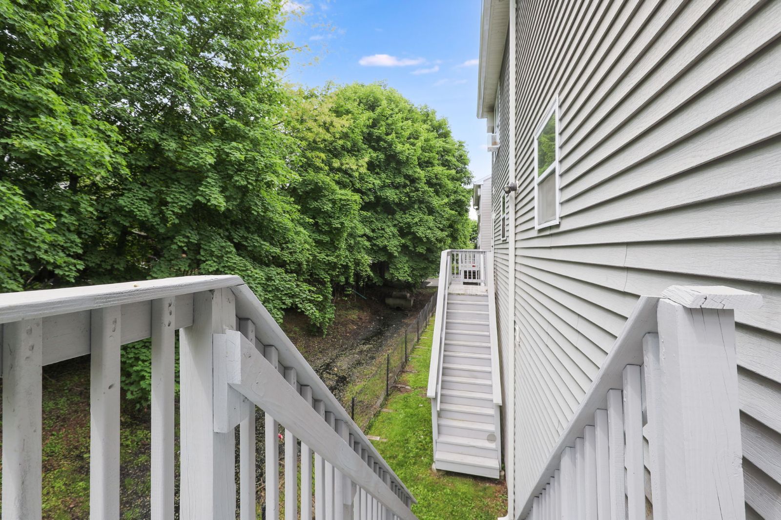Rear deck railing overlooking trees, with back stairs alongside