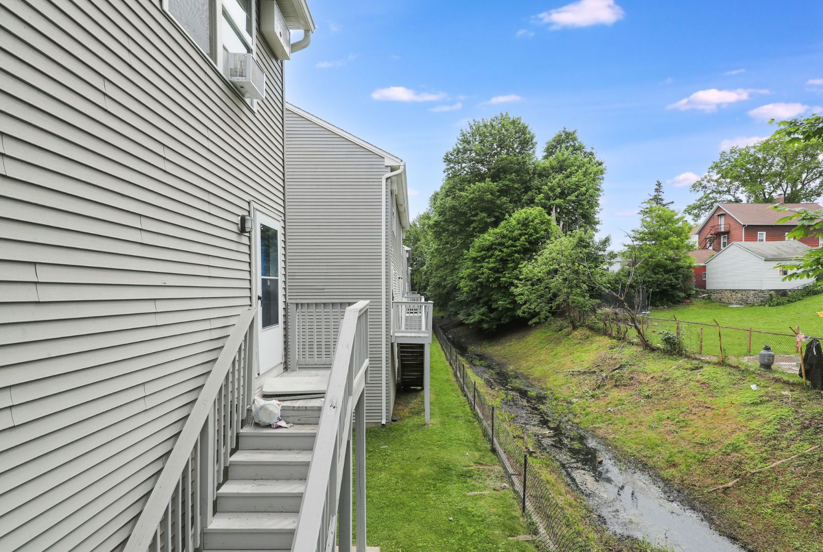 Back of the townhomes with rear stairs and a green yard